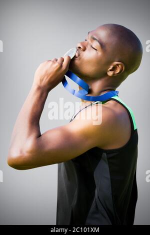 Composite image athletic man kissing sa médaille d'argent Banque D'Images