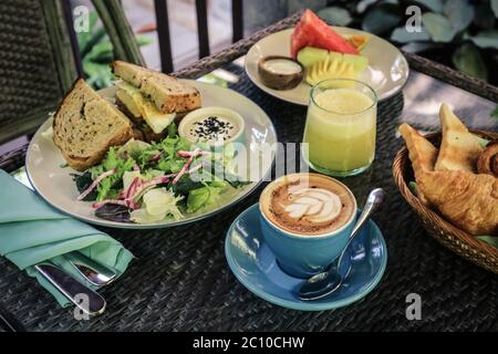 Sandwich, salade et panier à pain avec beurre, confiture et café sur table dans le café de la ferme. Concept petit déjeuner. Banque D'Images