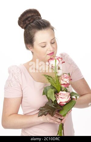 Jeune femme brune dans un chignon portant un bouquet de fleurs (roses) Banque D'Images