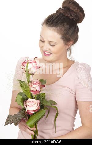 Jeune femme brune dans un chignon portant un bouquet de fleurs (roses) Banque D'Images