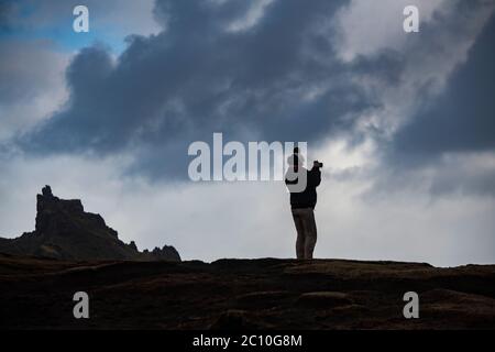 Un randonneur solitaire prend une photo dans la belle campagne des Highlands d'Écosse sur l'île de Skye Banque D'Images