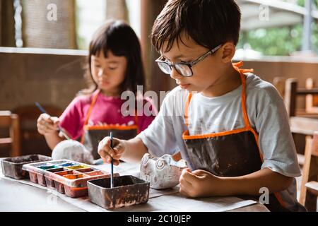 Garçon pageant de l'artisanat avec des couleurs dans la galerie de poterie avec des amis Banque D'Images