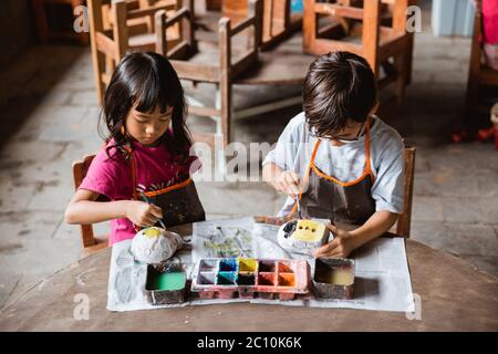 frère et sœur, peinture d'artisanat avec des couleurs dans la galerie de poterie avec des amis Banque D'Images