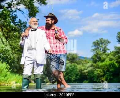 Pêche. Pêche à la mouche. Père à la retraite et fils mûrs avec barbe. Amis hommes avec canne à pêche et filet. Pêcheurs heureux dans l'eau. Passe-temps d'homme d'affaires. Pêche à la retraite. Banque D'Images