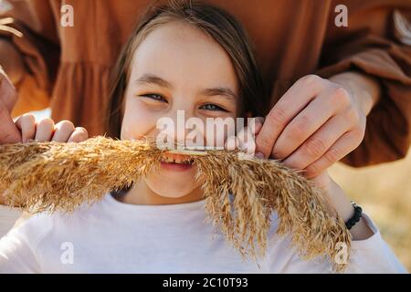 Maman tenant la moustache en céréales sur le visage de la petite fille. Elle est heureuse. Banque D'Images