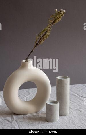 Composition de deux bougies aromatiques soufflées en verres en céramique blanche debout sur une table par vase artisanal créatif avec fleurs séchées Banque D'Images