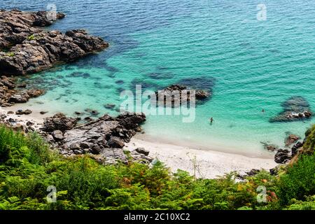 Crique cachée à Finisterre, en fin d'après-midi d'été en Galice, en Espagne, avec des baigneurs accessoires dans l'eau. Banque D'Images