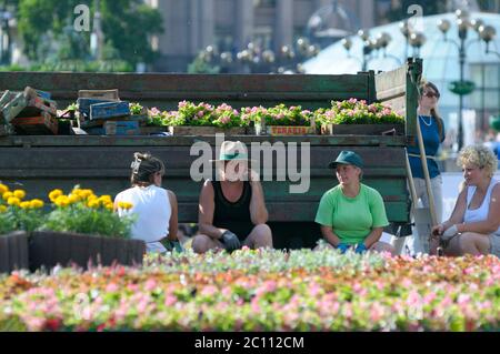 Les femmes des employés municipaux assis dans l'ombre ont été jetées par un camion qui s'est mis à prendre soin d'un lit de fleurs. 21 juin 2019. Kiev, Ukraine Banque D'Images