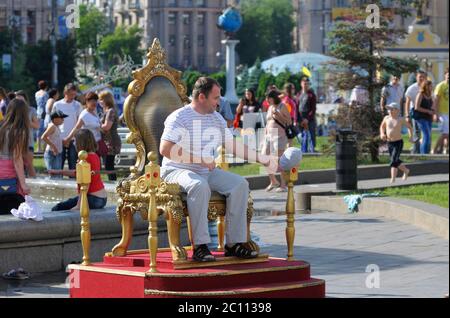 Homme assis dans le faux trône du roi, établi par l'artiste de rue pour photographier. 21 juin 2019. Kiev, Ukraine Banque D'Images