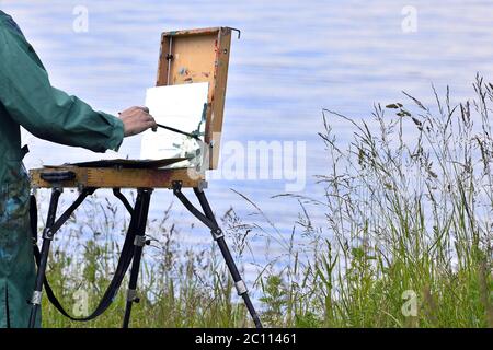 Mains de l'artiste à l'aide d'un pinceau, peindre un tableau sur un chevalet à l'air libre Banque D'Images