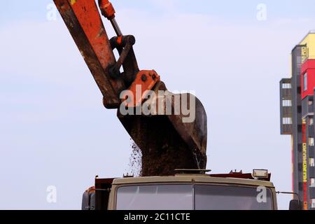 pelle hydraulique à chenilles, godet qui creuse de la tourbe pour la préparation des routes de construction terrestre et le charge dans un camion sur le chantier Banque D'Images