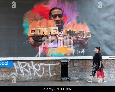 Londres, Royaume-Uni. 13 juin 2020. Les gens de Shepherd Bush marchent devant une grande affiche avec une photo de George Floyd portant un anneau avec les mots « Love » et « Hate ». George Floyd est mort le 25 mai après qu'un policier ait appliqué une pression sur son cou, l'arrêtant de respirer. Credit: Tommy London/Alay Live News Banque D'Images