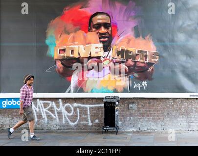 Londres, Royaume-Uni. 13 juin 2020. Les gens de Shepherd Bush marchent devant une grande affiche avec une photo de George Floyd portant un anneau avec les mots « Love » et « Hate ». George Floyd est mort le 25 mai après qu'un policier ait appliqué une pression sur son cou, l'arrêtant de respirer. Credit: Tommy London/Alay Live News Banque D'Images