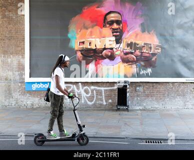 Londres, Royaume-Uni. 13 juin 2020. Les gens de Shepherd Bush marchent devant une grande affiche avec une photo de George Floyd portant un anneau avec les mots « Love » et « Hate ». George Floyd est mort le 25 mai après qu'un policier ait appliqué une pression sur son cou, l'arrêtant de respirer. Credit: Tommy London/Alay Live News Banque D'Images