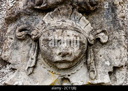 Gros plan d'une vieille sculpture de pierre de bas-relief dépeignant le visage d'une personne portant une headaddress. Banque D'Images