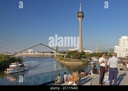 Les gens sur une terrasse de restaurant avec vue sur la tour du Rhin, Düsseldorf, Allemagne Banque D'Images