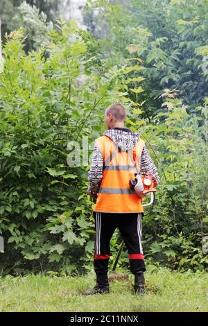 Un travailleur en uniforme tond la tondeuse à gazon. Banque D'Images