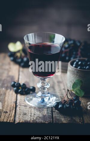 Aronie noire maison vin ou liqueur aux fruits mûrs sur fond de bois Banque D'Images