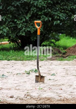 pelle de travail, avec la poignée orange coincée dans le sable Banque D'Images