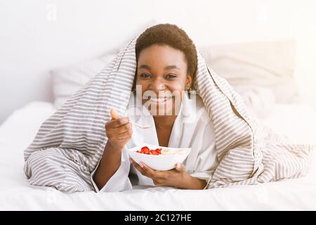 Une alimentation saine. Bonne fille afro-américaine a le petit déjeuner, manger de la salade le matin Banque D'Images