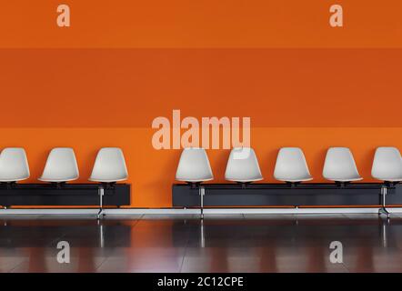 Chaises blanches dans une rangée contre un mur orange à l'intérieur d'un bâtiment moderne. Vider les chaises dans une salle d'attente Banque D'Images