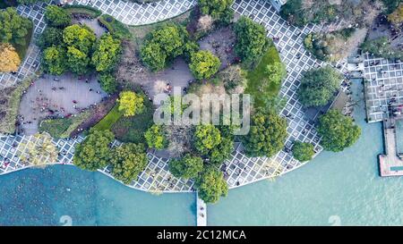 Vue aérienne de haut en bas sur le jardin de style chinois plein d'arbres, d'espaces ouverts, de tuiles géométriques entourées par les eaux du lac. Banque D'Images