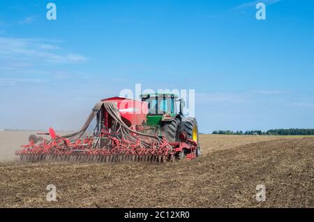 Tracteur agricole et de l'arrière du semoir travaillant dans un domaine Lituanien Banque D'Images