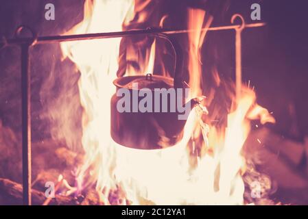 La bouilloire est chauffée sur un feu lumineux la nuit en extérieur, photo tonifiée Banque D'Images