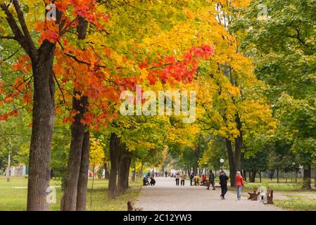 Les gens qui marchent le long de l'allée dans le parc avec des temples jaunes et rouges en automne Banque D'Images