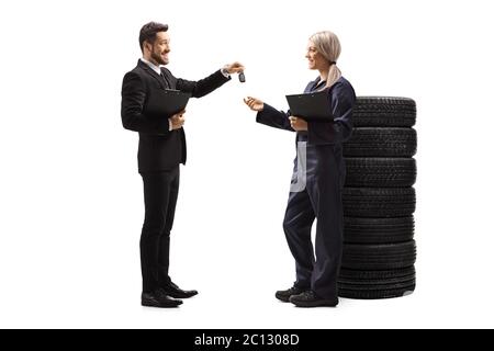 Photo pleine longueur d'un homme d'affaires qui a remis les clés d'une voiture à une mécanicien automobile femelle isolée sur fond blanc Banque D'Images