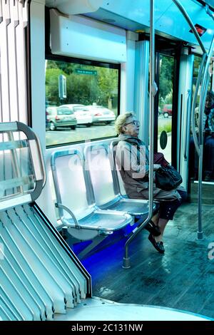 Femme âgée assise dans un bus futuriste avec sièges éclairés, Biarritz, France Banque D'Images