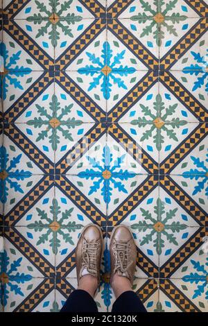 Les pieds d'une femme portent des baskets dorées sur un sol carrelé marocain traditionnel à Marrakech, au Maroc Banque D'Images