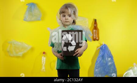 Triste activiste fille dans t-shirt avec le logo de recyclage dans des emballages en plastique sur son cou et la tête. Fond avec sacs de cellophane, flacons. Réduire la pollution par les déchets de plastique. Pensez vert. Sauver l'environnement écologique Banque D'Images