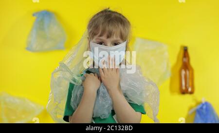 Triste activiste fille dans t-shirt avec le logo de recyclage dans des emballages en plastique sur son cou et la tête. Fond avec sacs de cellophane, flacons. Réduire la pollution par les déchets de plastique. Pensez vert. Sauver l'environnement écologique Banque D'Images