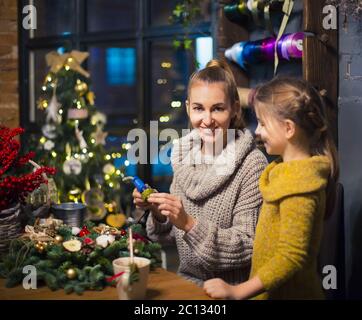 Femme avec fille décorant couronne de conifères Banque D'Images