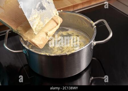 Cuisine de spaetzle maison, la pâte aux pâtes aux œufs est rebuté d'un panneau de bois dans une casserole avec de l'eau bouillante, plat typique à Schwaben, dans le sud de l'Allemagne A. Banque D'Images