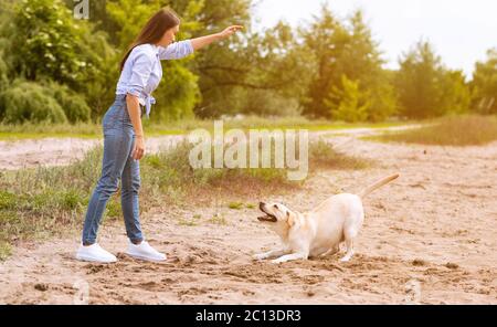 Femme donnant un commandement à son chien obéissant Banque D'Images