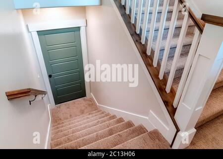 Escalier en U recouvert de moquette qui mène à la porte du sous-sol d'une maison Banque D'Images