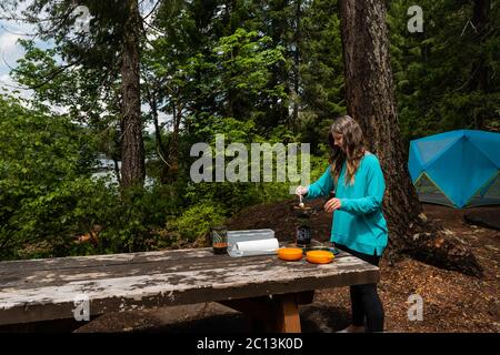 Une femme d'âge moyen préparant un repas pour deux sur un Jetboil pendant le camping Banque D'Images