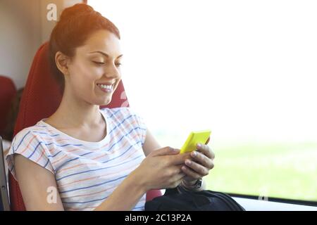 Jolie femme voyageant en train assis près de la fenêtre à l'aide d'un smartphone Banque D'Images