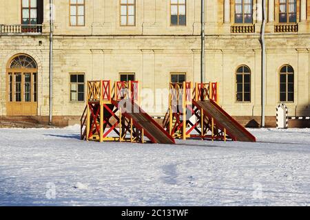 Deux toboggans en bois rouge et jaune pour enfants construits sur la place en face du palais en hiver. Banque D'Images