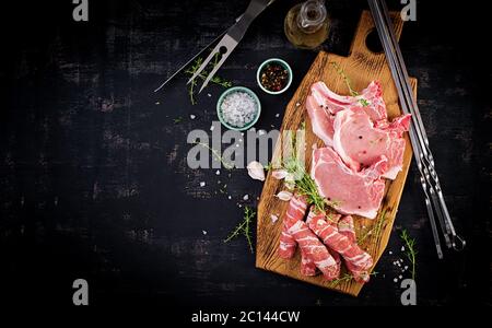 Steaks de porc crus. Différents types de viande de porc crue et de saucisses hachées se sont fait l'image de la table noire. Vue de dessus, au-dessus, espace de copie Banque D'Images