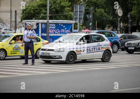 Bucarest, Roumanie - 13 juin 2020 : policier roumain près d'une voiture de police dans le centre-ville de Bucarest. Banque D'Images