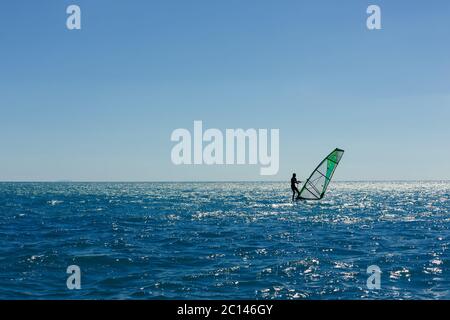 silhouette panoramique de planche à voile contre une mer bleue pémante Banque D'Images