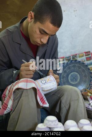 Un marocain peint un bol dans une usine de poterie à Fès, au Maroc. Banque D'Images