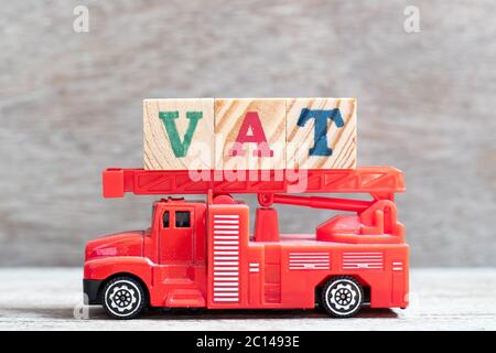 Camion rouge de pompiers tenir le bloc de lettres dans le mot TVA (abréviation de taxe sur la valeur ajoutée) sur fond de bois Banque D'Images
