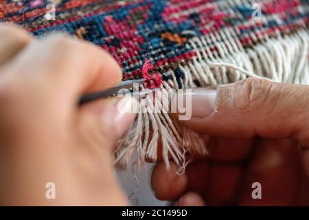 couture traditionnelle à la main fixant vieux vieux vieux tapis persan antique de près Banque D'Images