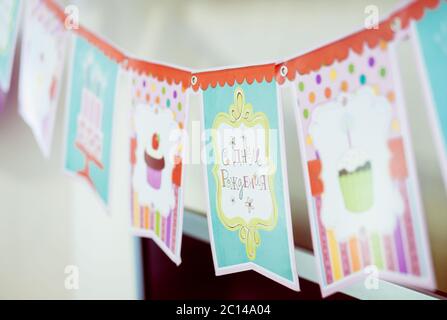 Vue rapprochée des drapeaux d'anniversaire colorés, guirlande avec des images de gâteau, bougies. Joyeux anniversaire en russe. Banque D'Images