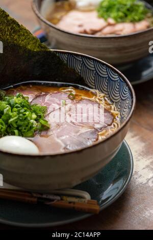 ramen asiatique avec nouilles de viande de porc bouillon de ciboulette oeuf et nori sur un bol traditionnel avec fond coloré peu profond Banque D'Images