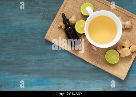 Tasse de thé avec des tranches de citron et des morceaux de gingembre sur fond bleu, , bouteille de gouttes Banque D'Images